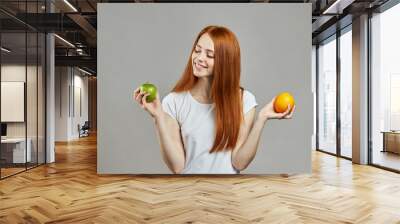 smiling cheerful girl comparing apple and orange. close up portrait. fresh fruit. Wall mural