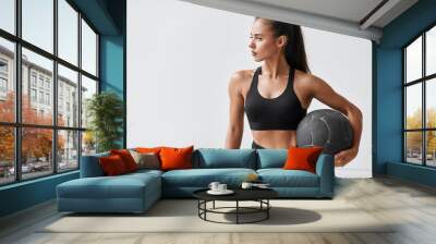 Sportive caucasian cross fit woman with fitness ball stand in gym, look. White wall background Wall mural