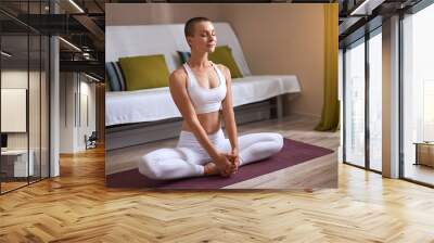 Sportive caucasian with short hair sit in lotus pose and keep calm with closed eyes. Wall mural