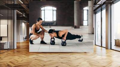 strong motivated man doing plank with kettlebells during workout at gym while his girlfriend looking at him. hobby, interest, motivation Wall mural