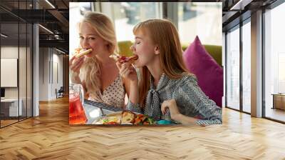 two young attractive women eat tasty pizza in cafe, have meal, delicious food. in light cafe Wall mural