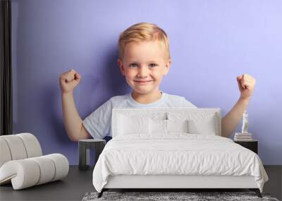 Winner kid isolated over purple background, show how powerful he is. Isolated over purple background Wall mural