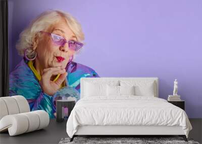 woman drink beverage from colourful bottle, party time. senior lady im blue coat and stylish sunglasses posing at camera, isolated Wall mural