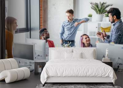 Young African constructor sharing new ideas about project to his partners in office working room. Multiethnic coworkers discussing over new business project in modern loft interior. Wall mural