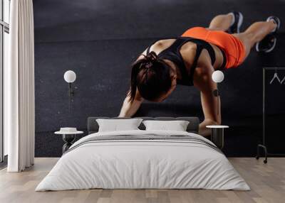 young beautiful woman in sportswear doing plank while trainnig at cross fit gym Wall mural