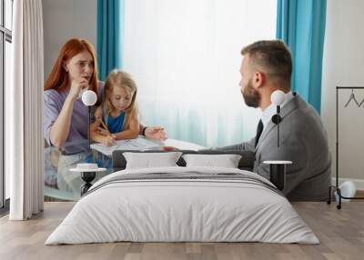 young depressed caucasian woman with child girl get support by psychologist, they sit at table talking, woman with red hair explain her problem and situation Wall mural