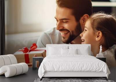 A little girl sits next to her father on the sofa and gives him a gift box Wall mural