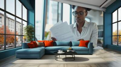 Focused Businesswoman Reading Documents at Desk Wall mural