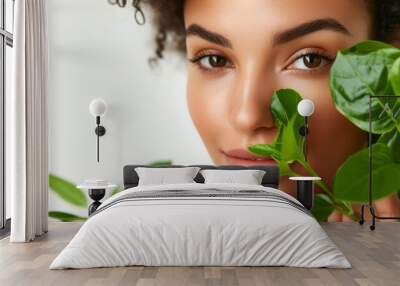 Woman holding green leaves near her face in a studio Wall mural