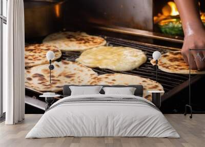 hand placing peshwari naan on a hot griddle for cooking Wall mural