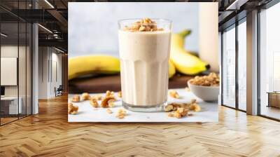 walnut pieces on top of a banana smoothie in a clear glass Wall mural