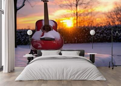 wintery sunset behind a snow covered acoustic guitar on stand Wall mural