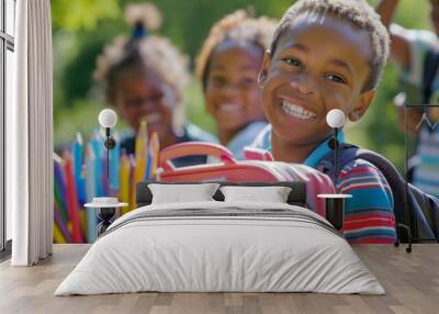 A young boy is smiling and holding a backpack with school supplies Wall mural