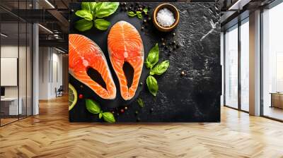 Raw salmon steaks with basil leaves, lemon slices, and a small bowl of salt on a textured dark background. Wall mural