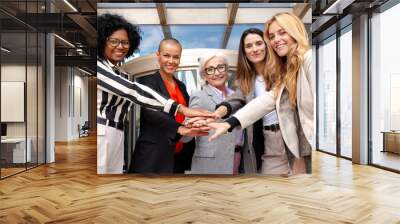 Close-up of diverse businesswomen clasping hands outdoors. Wall mural