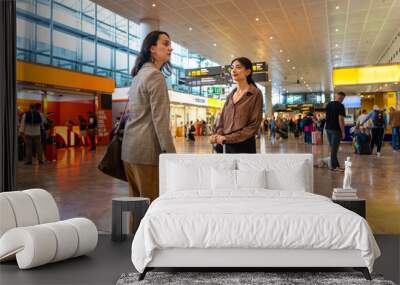 Two interracial businesswomen waiting for their flight at the airport Wall mural