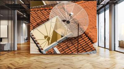 Satellite dish on the roof tile.Parabolic antenna, an antenna for catching domestic and foreign TV broadcasts, mounted on the roof of a building, in Brazil Wall mural