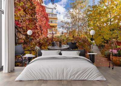 Cozy autumn courtyard with a table, rattan chairs, chrysanthemums in pots. Wall mural