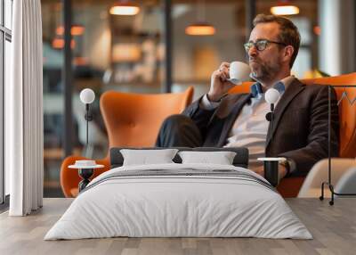 a businessman taking a brief break in a modern office lounge area, sipping coffee while seated in a comfortable chair. The environment is relaxed yet stylish, with soft lighting  Wall mural