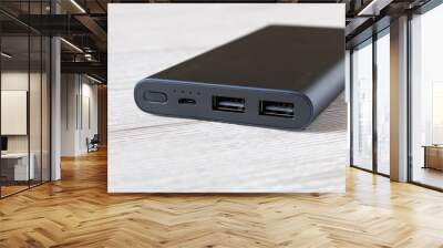 Black power Bank for charging mobile devices on wooden table. Wall mural