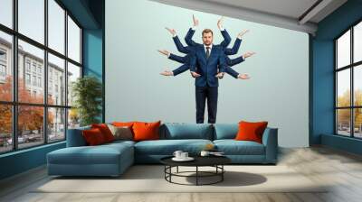 Businessman with many hands in a suit. Works simultaneously with several objects, a mug, a magnifying glass, papers, a contract, a telephone. Multitasking, efficient business worker concept. Wall mural