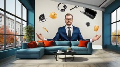 Businessman with many hands in a suit. Works simultaneously with several objects, a mug, a magnifying glass, papers, a contract, a telephone. Multitasking, efficient business worker concept. Wall mural