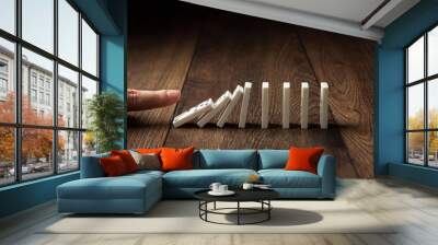 Creative background, Male hand pushing white dominoes, on a brown wooden background. Concept of domino effect, chain reaction, copy space. Wall mural