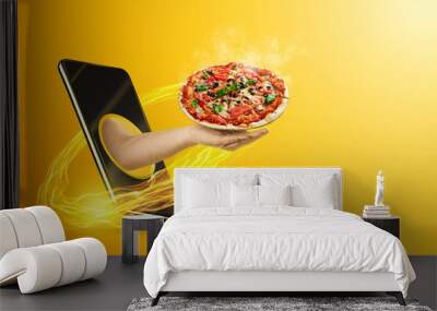 Hand serves pizza via smartphone on yellow background. The concept of food delivery, online ordering, restaurant services at home. Wall mural