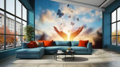 Hands close up on the background of a beautiful sunset, a flock of butterflies flies, enjoying nature. The concept of hope, faith, religion, a symbol of hope and freedom. Wall mural