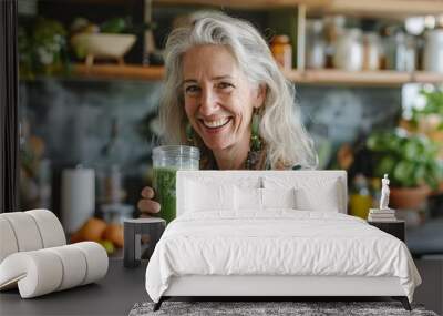 A woman is smiling and holding a green smoothie in a glass Wall mural