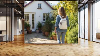 rear view of college student carrying backpack back home using door with key. young office lady from work unlock the house to enter the room. two plants next to the front door in a white wooden house Wall mural