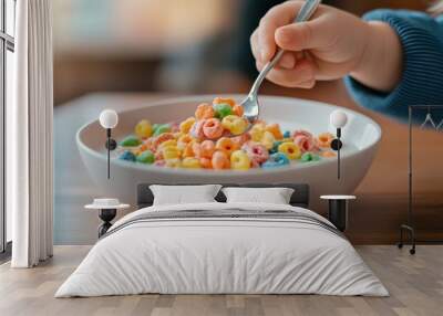 A child is eating a bowl of colorful cereal with a spoon Wall mural