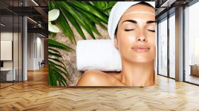 A woman is laying on a towel with a white bandana on her head Wall mural