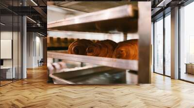 Production of delicious buns. Family bakery. Hot croissants on a metal tray. Fresh bakery. Rack with baked croissants. Wall mural