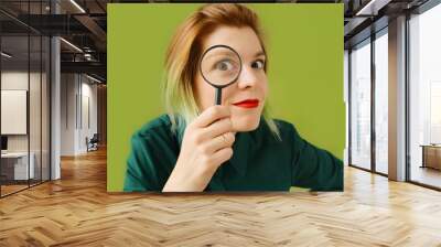 Search. A young woman with a magnifying glass searches, investigates and studies. Wall mural