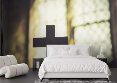 Silhouette of cross, symbol of Christian faith, inside a sacred church in front of a beautiful antique stained glass window. Warm light. Easter holy week Good Friday concept. Wall mural