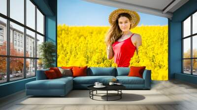 Young woman in blooming rapeseed field in spring. Wall mural