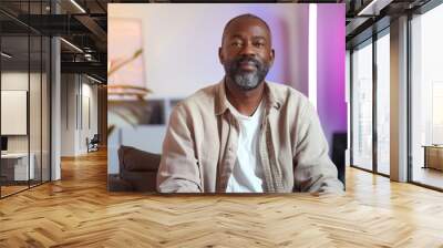 A 40 year old professional black man in neutral clothing sitting in a video recording studio Wall mural