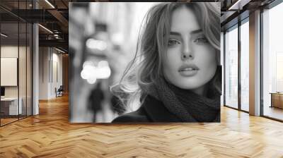 A black-and-white portrait of a woman with wavy hair, wearing a scarf in an urban setting. Wall mural