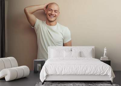 Bald young man in casual attire smiling with a relaxed and confident pose against a neutral background Wall mural