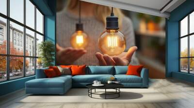 Woman holding two glowing Edison light bulbs in her hands. Wall mural