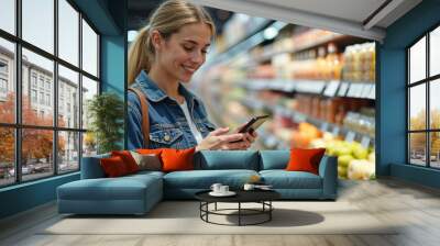 Happy woman using reminder on smart phone while shopping in supermarket. Wall mural