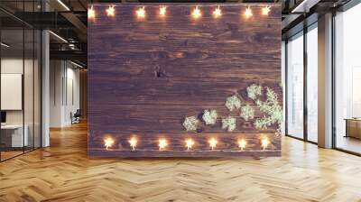 Christmas warm gold garland lights with snowflakes on wooden rustic background. Christmas or New Year concept Blur christmas lights on wooden planks. Wall mural