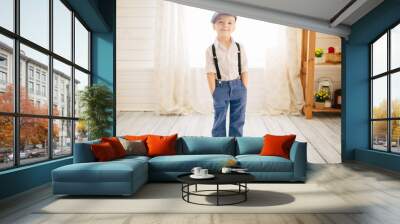 Cute boy in a white shirt, cap and suspenders in a bright room. Retro style in clothes Wall mural