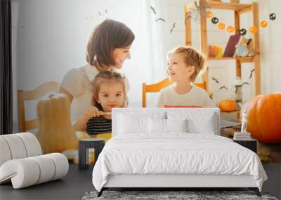 family mother and child daughter in hat witch are preparing for halloween carve a pumpkin and decora Wall mural