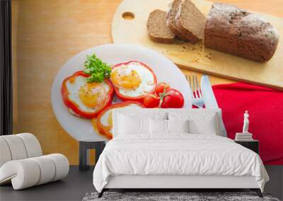 Fried eggs in paprika served on white plate on wooden background Wall mural