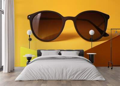 Closeup photo of brown sunglasses on a yellow stylish background Wall mural