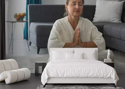 A beautiful middle-aged woman in a white outfit is doing exercises and meditations Wall mural