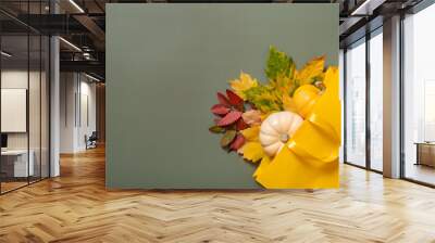 Autumn shopping and sales flat lay concept. Composition of autumn fallen leaves and a shopping bag on a green background Wall mural