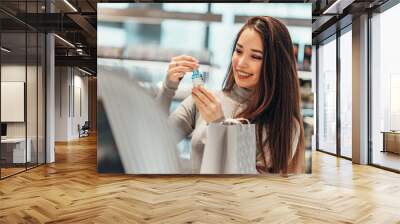 beautiful smiling Asian girl chooses and buys face serum cosmetics in the store. shopping Wall mural